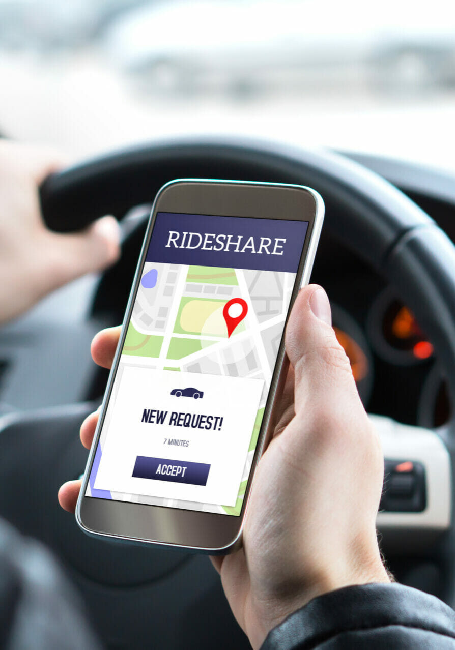 Ride share driver in car using the rideshare app in mobile phone. New taxi ride request from customer in smartphone application. Man picking up passengers for online carpool service.